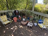 Full deck view with chairs, large urn planter, assortment of pots, driftwood and decor