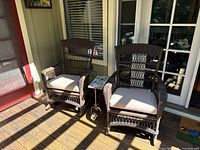 Two wicker rocking chairs with cushions and side table