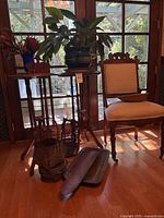 Two wood plant stands with plant, chair, baskets, trays visible