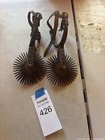 Full view of both spurs showing size, rowels, and leather straps