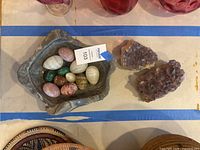 Marble bowl with gemstone eggs beside two amethyst clusters
