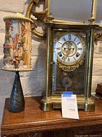 Mantle clock alongside decorative candle on pedestal