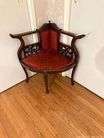 Overall view of vintage corner dressing chair showing wood frame, red velvet upholstery, carved details