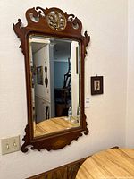 Front view of carved wooden mirror and framed silhouette on wall