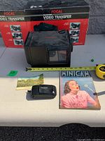 Group shot showing projector, box, camera, magazine and postcard