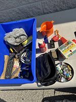 Overview of tote with camera, pitcher, remotes and various small items