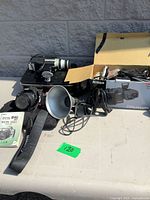 Overall lot showing three cameras, lenses, Nikon box, metal case, reflector bowl, manuals and accessories on table