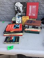 Stack of assorted vintage books on table showing variety and quantity