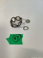 Bracelet coiled beside dime and loose D-shaped link