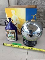 Full view of chrome sphere bar set, blue vermouth jug, and modernist plaque with tape measure for scale