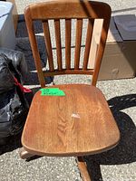 Front view of oak swivel chair showing seat, back slats, medium brown finish