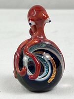 Front view of red glass octopus on multicolor sphere
