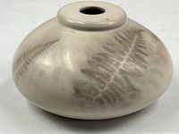 side view of squat cream ceramic vase with fern leaf imprints
