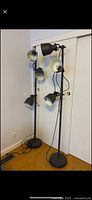Two identical black metal floor lamps each with three adjustable spotlight heads