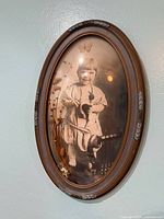 Full view of oval bubble glass frame with child photograph, dried flowers and butterfly