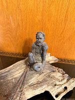 Front view of pottery figure on driftwood