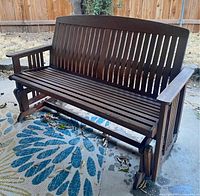 Full view of teak wood glider bench showing slatted design and glider base
