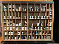 Overall view of filled wooden display case showing majority of thimbles