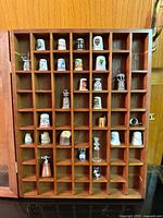 Full view of open wooden display case with thimbles