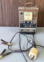 Front view of Fox 6-volt battery charger with attached cords and clamps