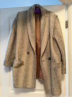 Full view of the front of the wool herringbone coat hanging