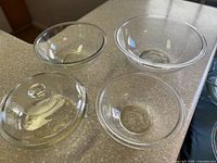 Three clear glass bowls and one clear glass lid on countertop