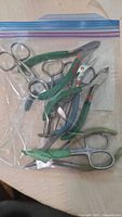 zip bag containing multiple stainless pliers and cutters with taped handles