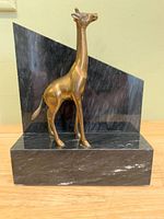 Brass giraffe figure mounted on angular black stone composite bookend, front view