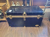 Front view of black Everlite trunk showing brass hardware and badge