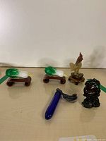 Group view of rooster, two bok choy carvings on stands and blue snuff bottle