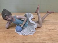 Profile view of porcelain ballerina figurine showing front details and ball