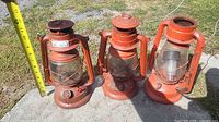 Front view of three red kerosene lanterns showing overall condition