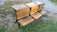 Three vintage cast-iron framed school desks showing tops and seats