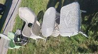 Four mixed-colour wicker armchairs and two white wicker side tables on lawn