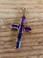 Front view of gold cross pendant showing amethyst baguettes