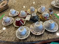 Overview of ten upside-down teacups with matching saucers on granite countertop