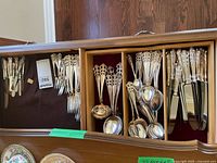 Flatware set arranged in chest showing forks, spoons, small knives