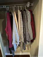 Closet rod with eight hanging sweaters/cardigans in assorted colours and patterns