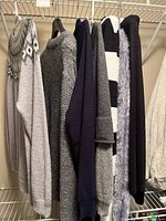 Group of seven sweaters hanging on rack