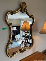 Front view of ornate gold-tone wall mirror hanging on wall