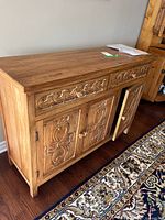 Front and side view of carved wood cabinet closed, showing drawers and doors