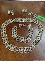 Entire set laid out showing necklace, bracelet, both earring pairs, extra link
