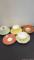 Group shot of 4 teacups with 5 saucers showing patterns and colours