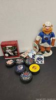 Group shot of plush bear, pucks, boxed item and trading cards