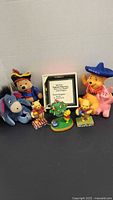 Group shot of all items in lot including bank, plush toys, figurines, framed quote
