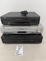 Three stacked video units: black JVC VCR, silver JVC VCR, black Sony combo