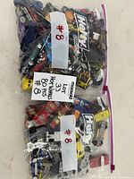 Both Hefty bags filled with Hot Wheels cars, lot label visible