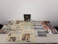 Overview of newspapers, magazine pages and framed photo arranged on table