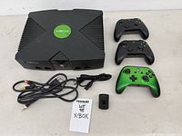 Front view of Xbox console, three controllers, cables and receiver