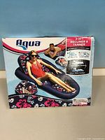 Front of sealed box displaying Aqua 2-in-1 Recliner & Tanner details and floral design
